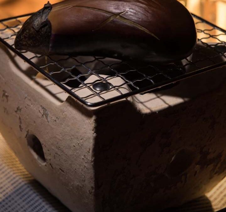 炭火でナスを焼いている写真