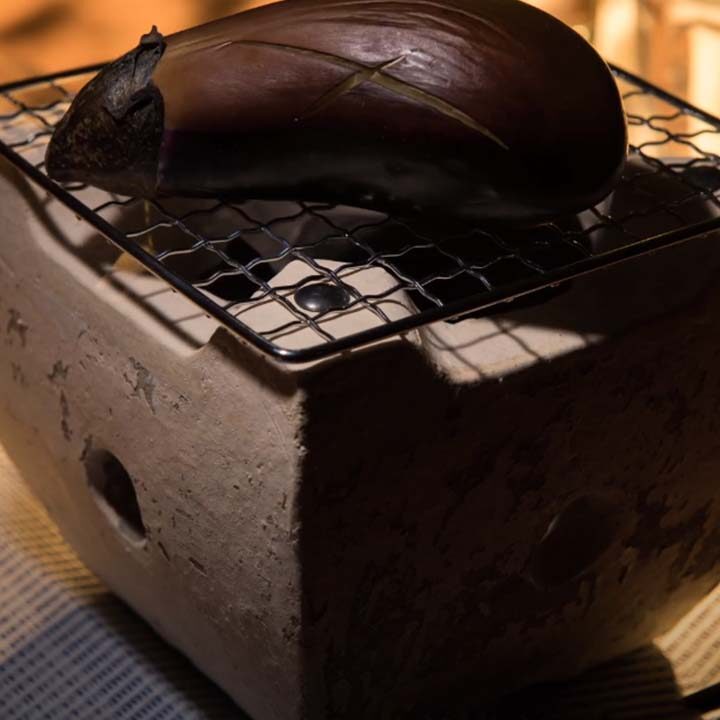 炭火でナスを焼いている写真