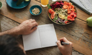 サラダを食べながらノートを書く女性の写真